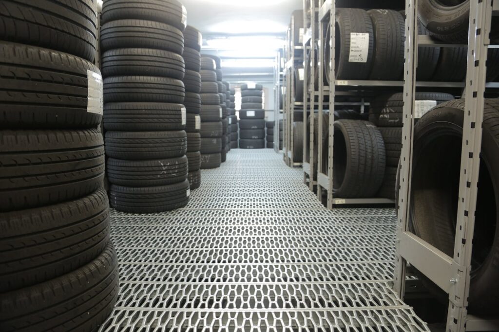 Rows of stacked tires in an indoor industrial warehouse for storage.